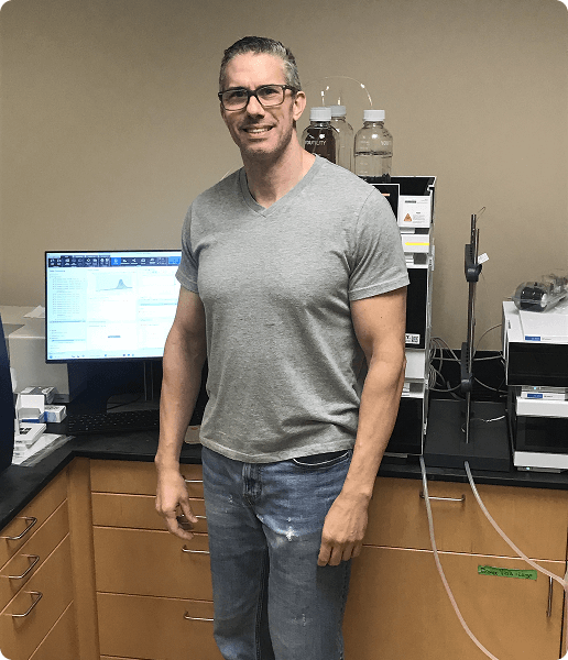 Anthony Prudden standing next to a high-pressure liquid chromatography machine.