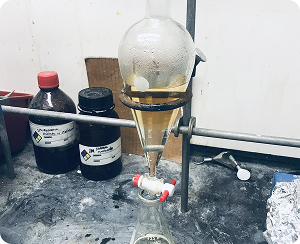 A 250 mL separatory funnel containing an organic and aqueous layer being held by a ring stand.